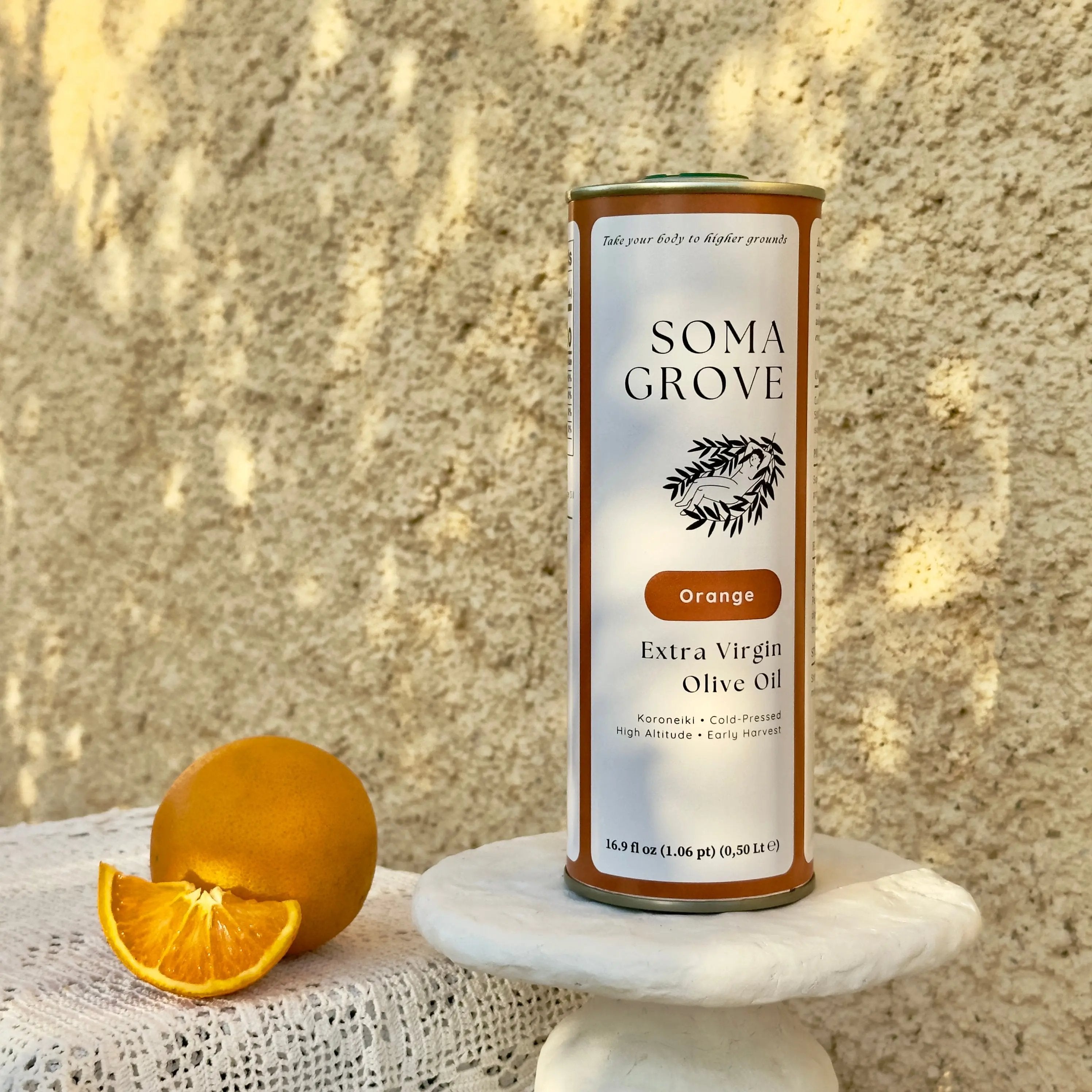 An outdoor setting with traditional Greek textiles and stone surfaces, featuring Orange Extra Virgin Olive Oil by Soma Grove.